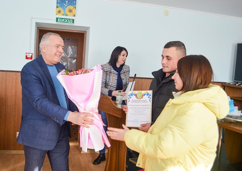 Міський голова Кагарлика Олександр Панюта вручає подарунковий сертифікат батькам Поліни Ігорю та Вікторії Бабатам