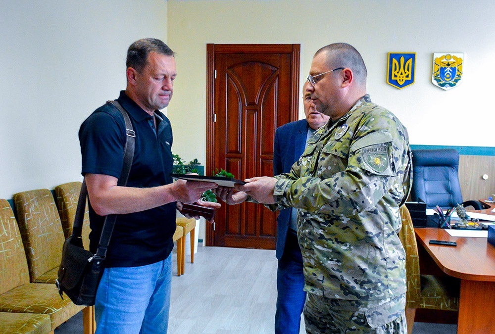 Підполковник поліції В’ячеслав Вусінський передає батьку загиблого Героя Мирослава Ярмішка Андрію Ярмішку «Комбатантський хрест» сина
