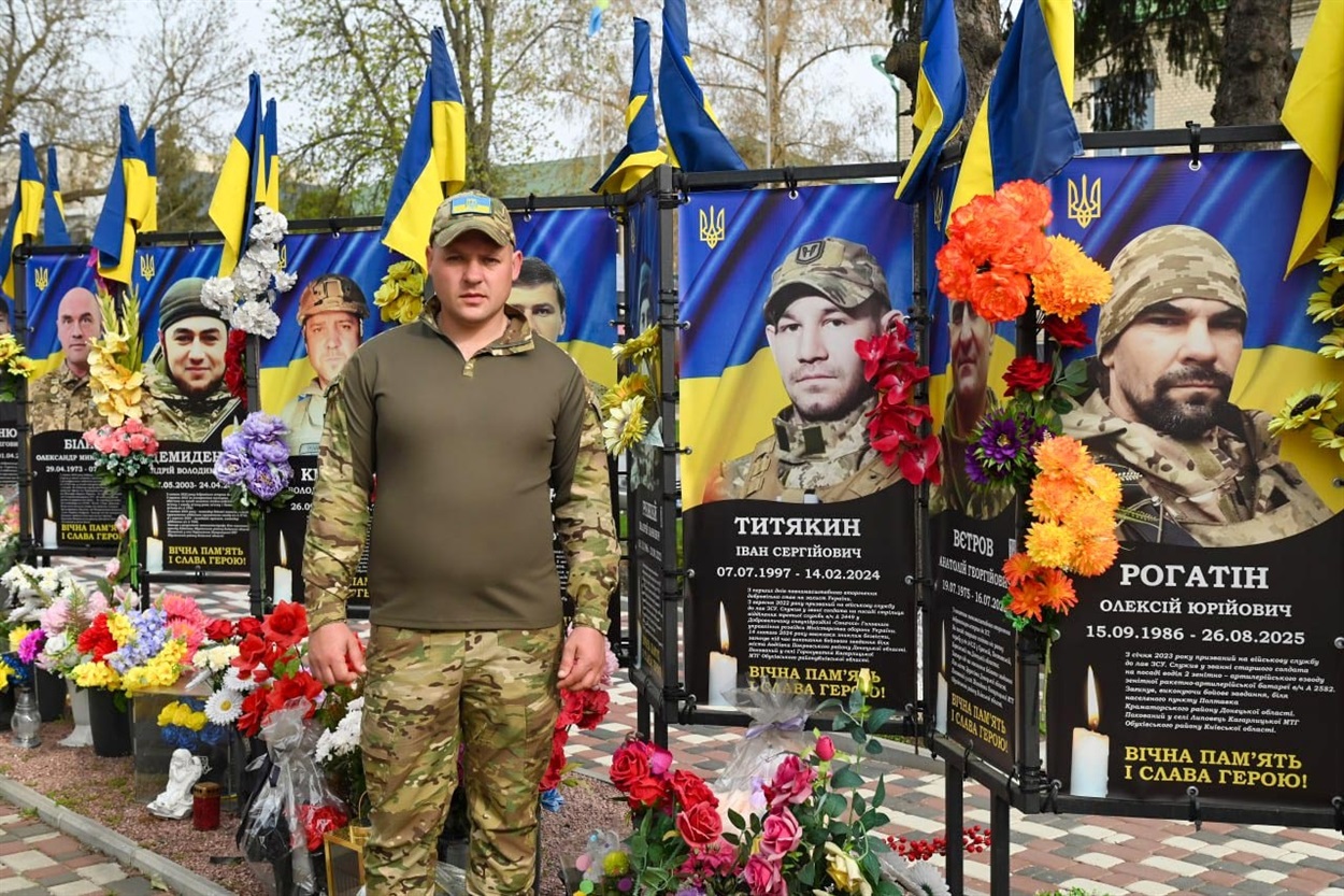 Роман Цівун на Алеї Слави Героїв в Кагарлику біля банера з портретом свого племінника, полеглого воїна Івана Титякіна