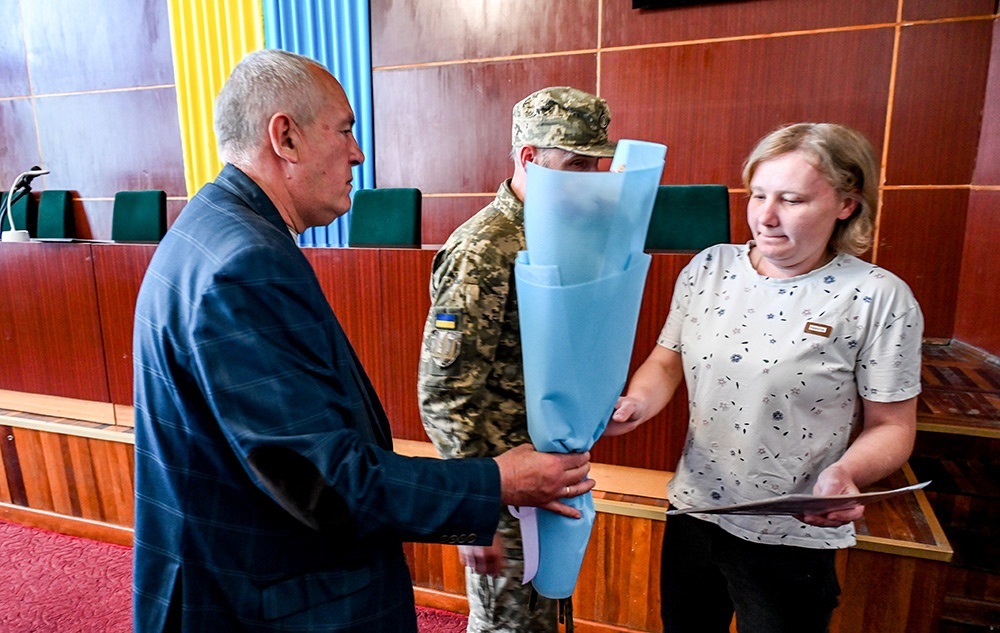 Кагарлицький міський голова Олександр Панюта вручає квіти дружині воїна Артема Сатиренка Марині